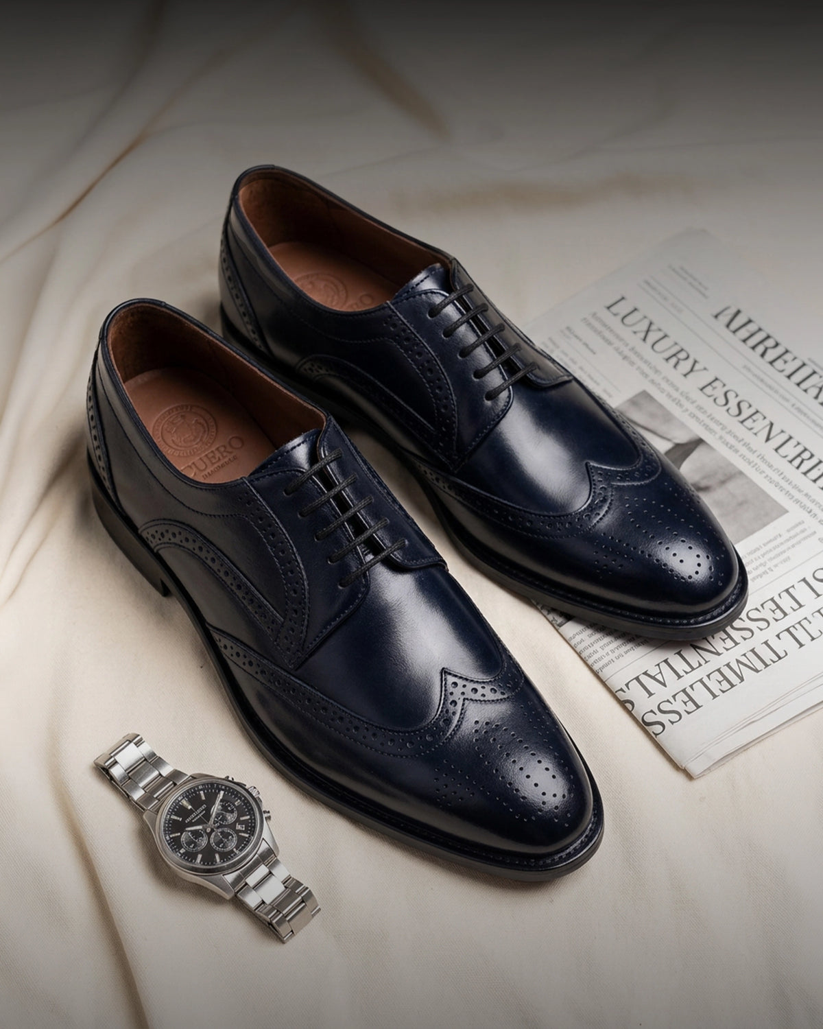 The Atlantic Brogue men’s navy leather dress shoes displayed with a silver watch for the Boardrooms collection