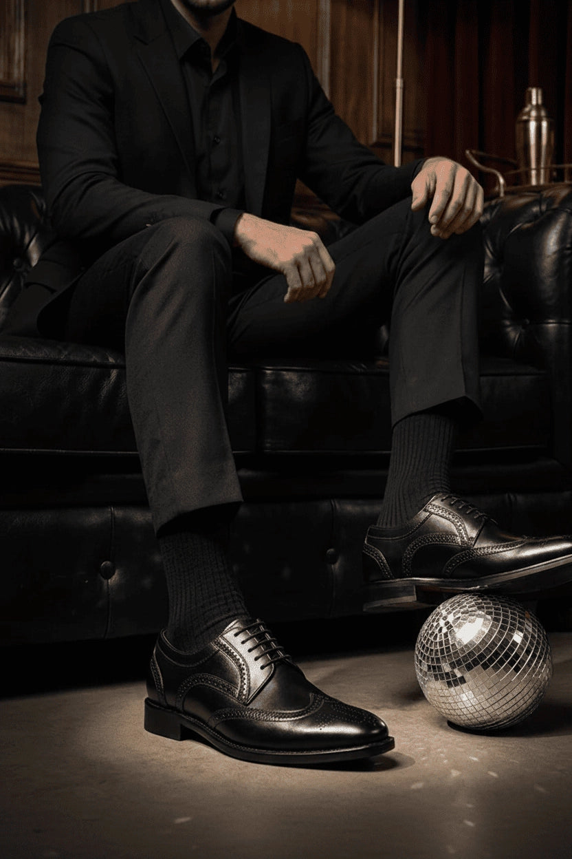 Man in a black suit wearing Black Oxonian polished leather Oxford shoes in a refined evening lounge