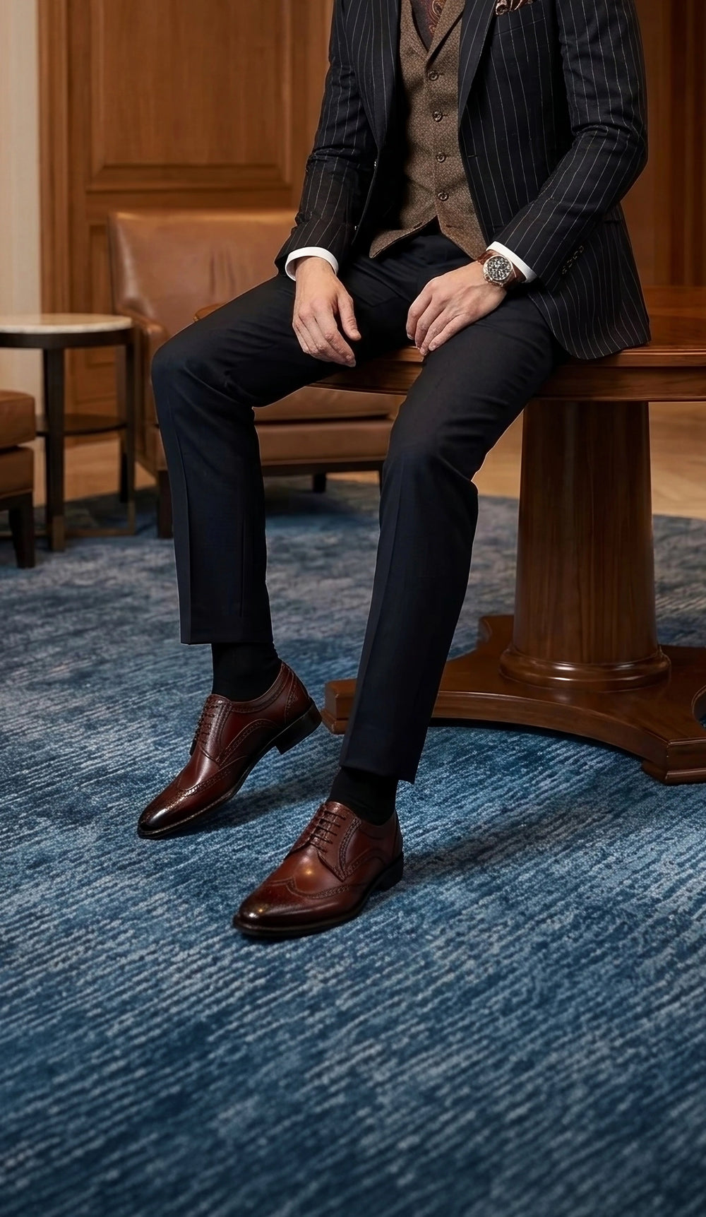 Man wearing burnished brown leather Oxford dress shoes with tailored business attire in an upscale lounge